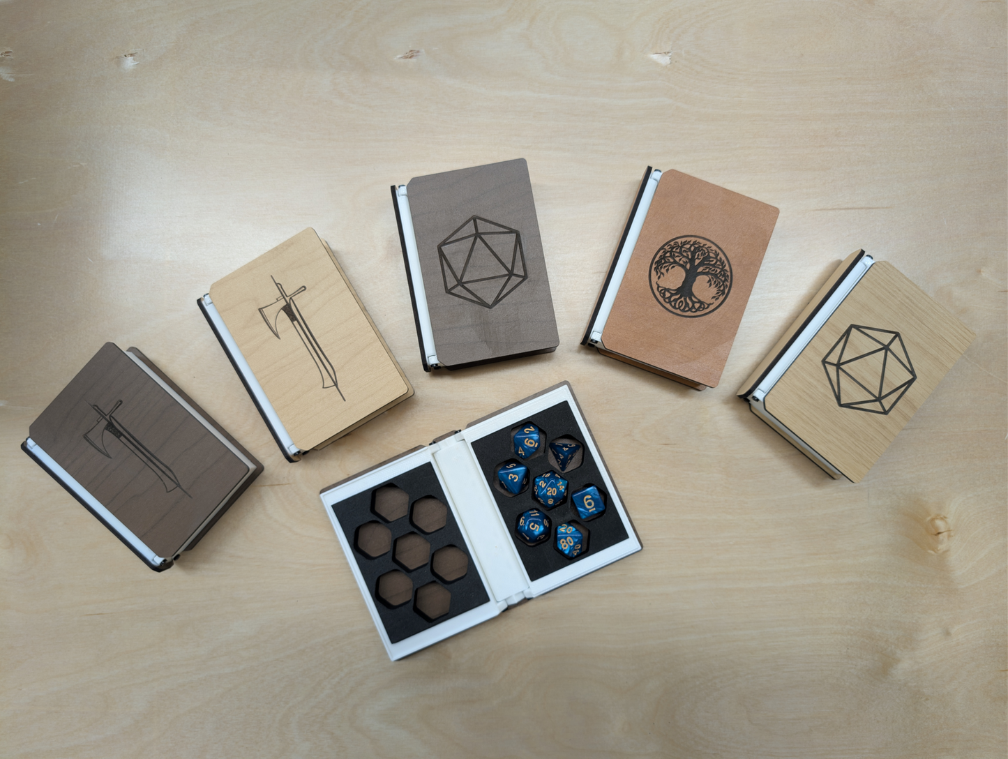 Set of wooden dice boxes with geometric designs on a light wood surface