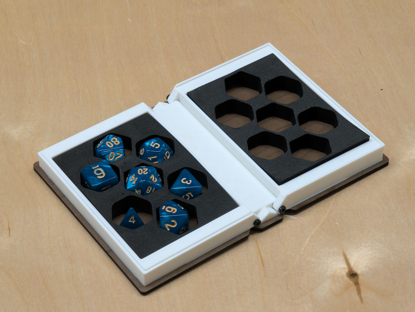 Set of blue dice with gold numbers in an opened box designed like a book.